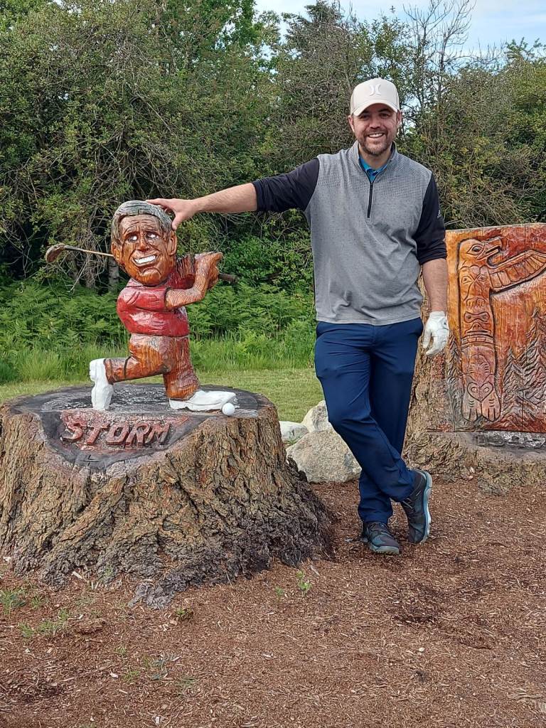 Golfer in a white cap posing with the course mascot.